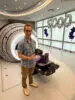 Christopher Czerwinski, the 5,000th patient treated with the ZAP-X® Gyroscopic Radiosurgery® platform, stands smiling beside the machine at Jersey Shore University Medical Center, holding a commemorative gift. Silver “5000” balloons are displayed in the background.