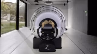 ZAP-X installation in modern room with concrete floor and mirrored ceiling. A floor-to-ceiling glass wall is behind the machine