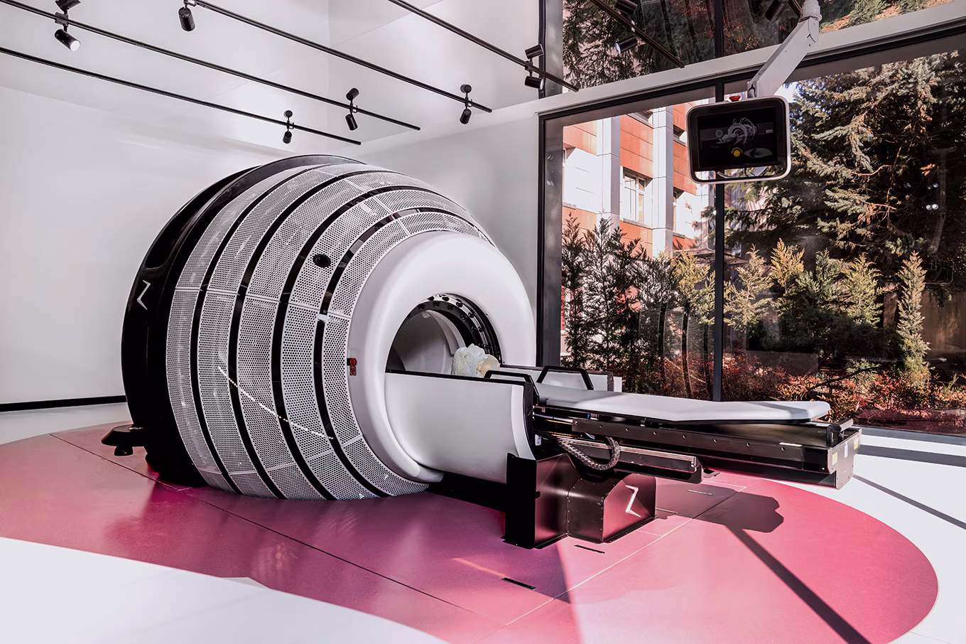 ALT text:A ZAP-X Gyroscopic Radiosurgery System is displayed in a clinical setting. The compact, self-shielded unit features a large spherical treatment head mounted on a rotating base, surrounded by clean, modern medical equipment and soft lighting. The machine’s design emphasizes precision, safety, and innovation in non-invasive brain tumor treatment.